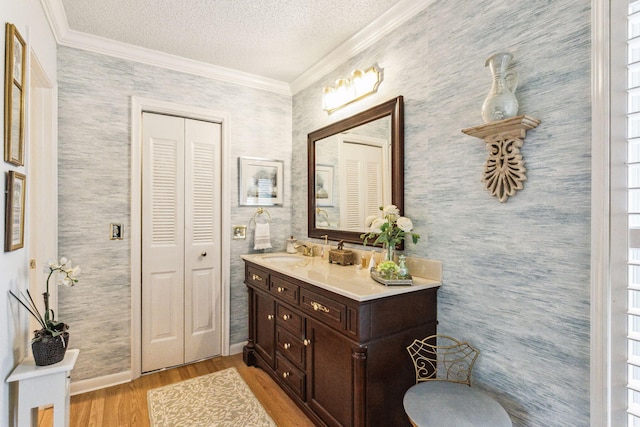 bathroom with vanity, wood-type flooring, a textured ceiling, and crown molding