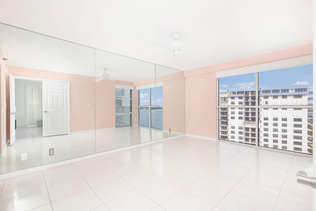 tiled empty room featuring a water view and ceiling fan