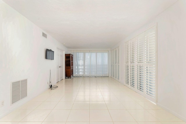 empty room with a textured ceiling and light tile patterned flooring