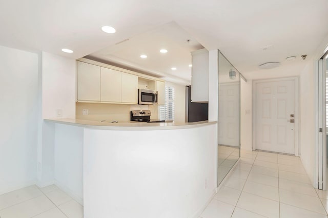 kitchen featuring white cabinetry, appliances with stainless steel finishes, light tile patterned flooring, and kitchen peninsula