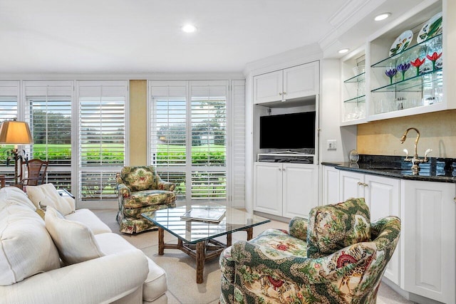 living room featuring indoor wet bar, light colored carpet, and crown molding