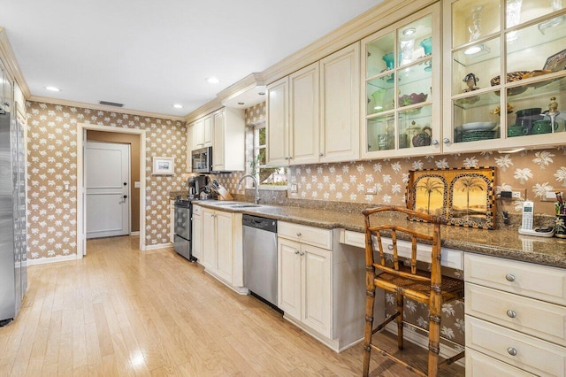 kitchen with stainless steel appliances, light hardwood / wood-style floors, crown molding, and dark stone countertops