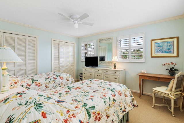 bedroom with ceiling fan, light carpet, multiple closets, and crown molding