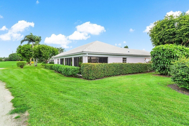 view of side of home featuring a sunroom and a yard