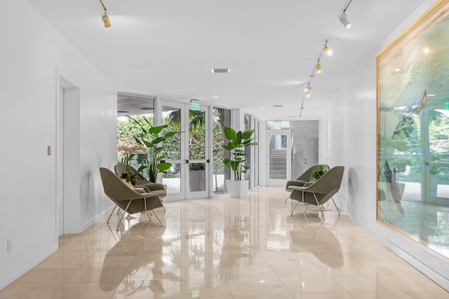 living area featuring french doors, rail lighting, visible vents, expansive windows, and baseboards