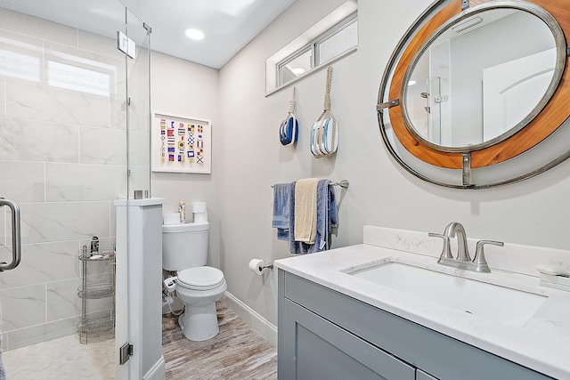 bathroom featuring wood-type flooring, vanity, a shower with shower door, and toilet