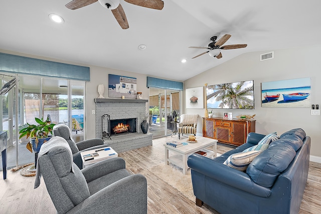 living room featuring a fireplace, light wood-type flooring, vaulted ceiling, and ceiling fan