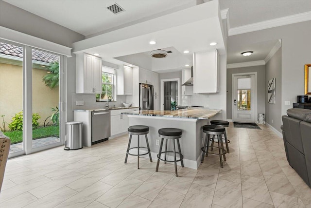 kitchen featuring tasteful backsplash, appliances with stainless steel finishes, white cabinets, sink, and a breakfast bar area