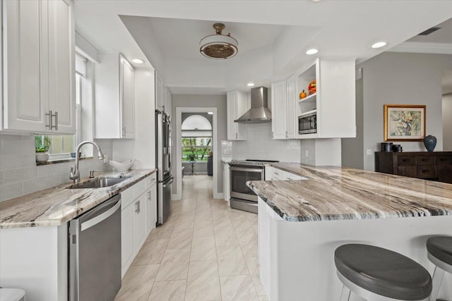 kitchen featuring wall chimney range hood, appliances with stainless steel finishes, sink, and light stone countertops