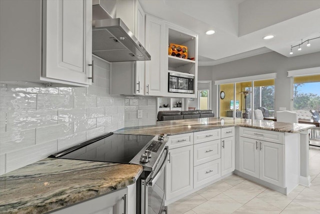 kitchen featuring electric stove, kitchen peninsula, stone counters, wall chimney range hood, and white cabinetry