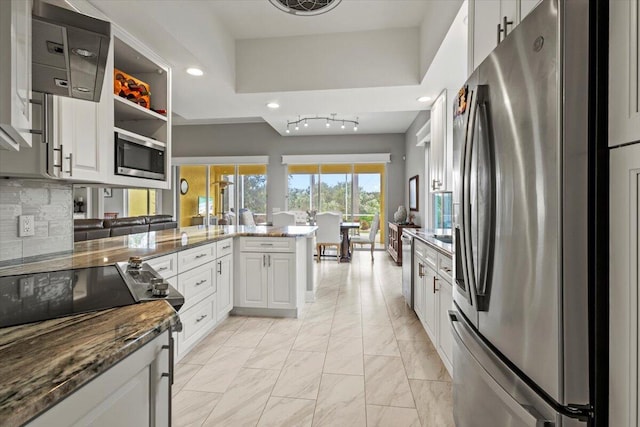 kitchen featuring kitchen peninsula, white cabinetry, decorative backsplash, and appliances with stainless steel finishes