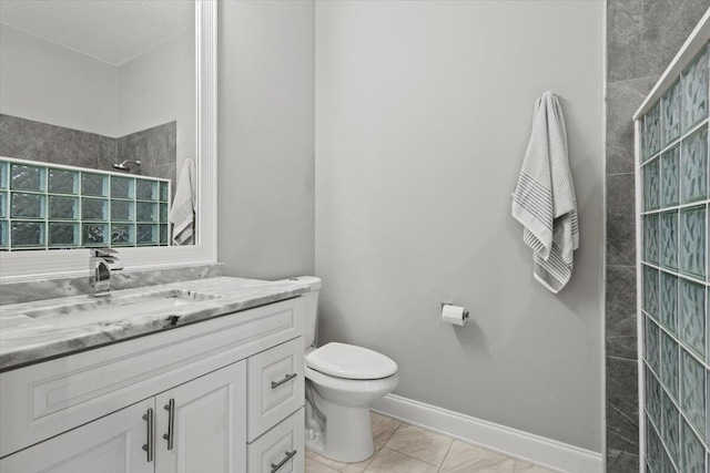 bathroom featuring vanity, tile patterned flooring, toilet, and tiled shower