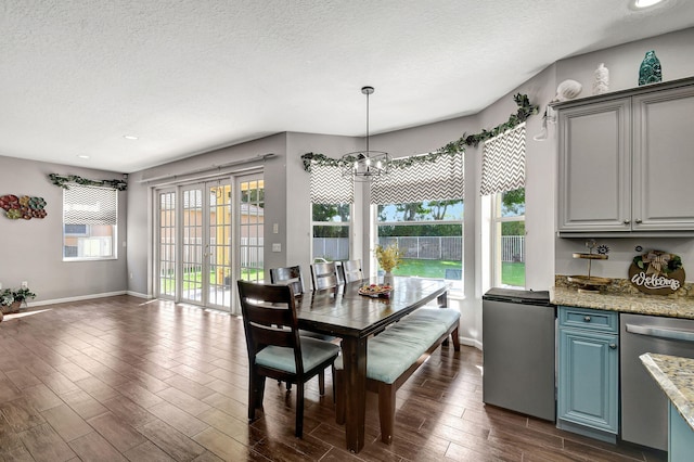 dining space with dark hardwood / wood-style flooring, a textured ceiling, and a notable chandelier