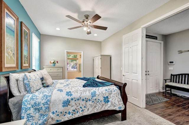 bedroom with ceiling fan, a textured ceiling, and dark hardwood / wood-style flooring