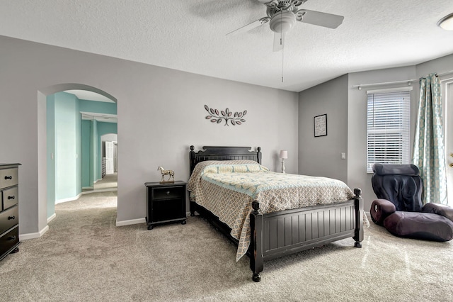 carpeted bedroom featuring ceiling fan and a textured ceiling