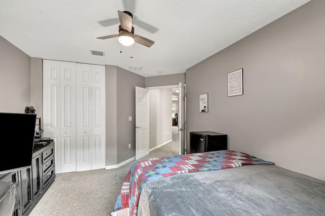 bedroom with a textured ceiling, ceiling fan, dark carpet, and a closet