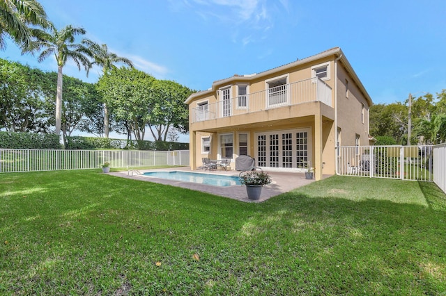 back of property featuring a fenced in pool, a lawn, french doors, and a balcony