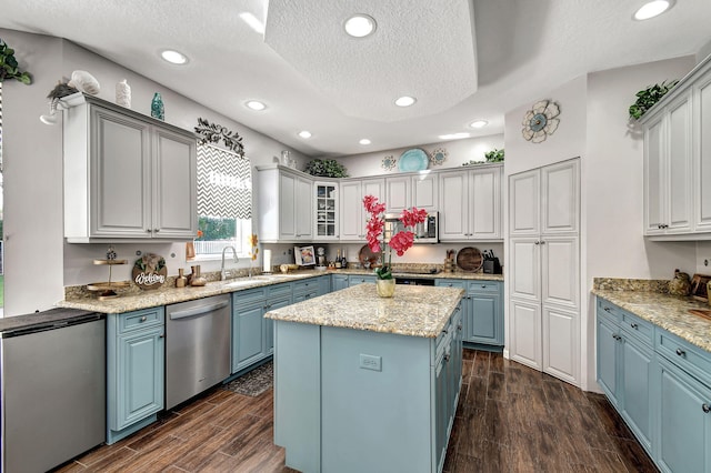 kitchen with appliances with stainless steel finishes, dark hardwood / wood-style floors, a textured ceiling, and a kitchen island