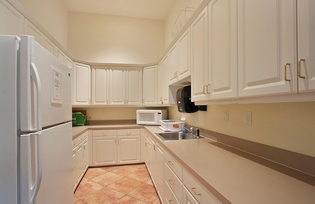 kitchen with white appliances, sink, light tile patterned floors, and white cabinets