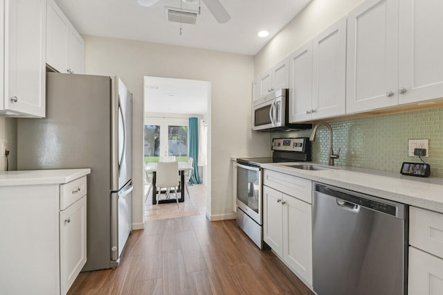 kitchen with sink, appliances with stainless steel finishes, dark wood-type flooring, and white cabinets