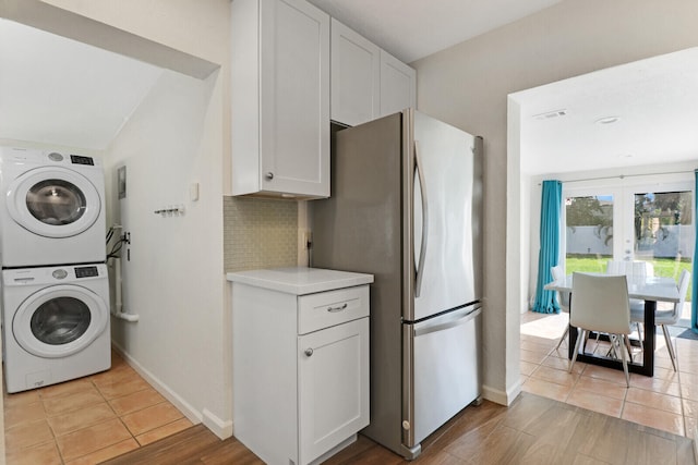 washroom featuring french doors, stacked washer and dryer, and light tile patterned floors