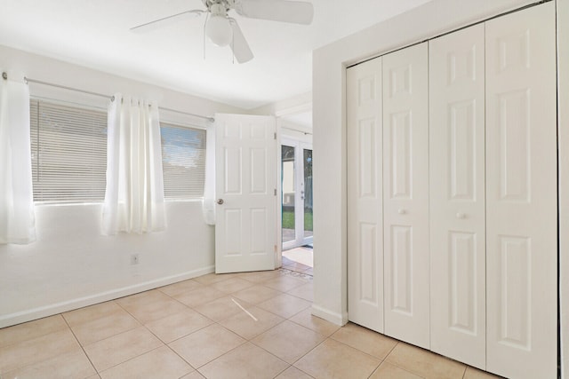 unfurnished bedroom with a closet, light tile patterned floors, and ceiling fan