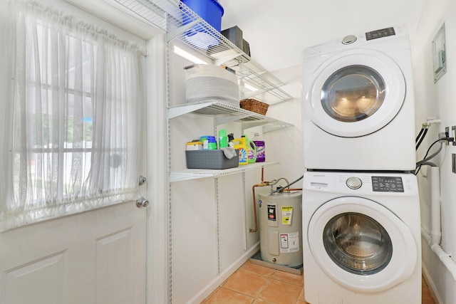 washroom with stacked washer / drying machine, electric water heater, and light tile patterned floors