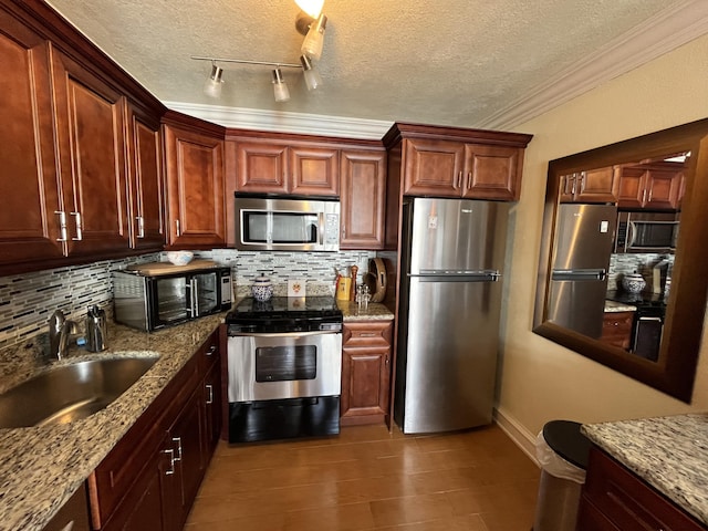 kitchen with backsplash, crown molding, stainless steel appliances, and a sink