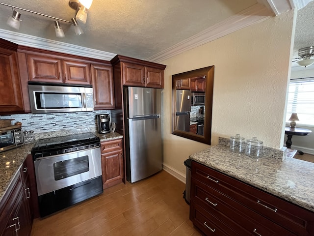 kitchen featuring a textured ceiling, stainless steel appliances, wood finished floors, ornamental molding, and tasteful backsplash