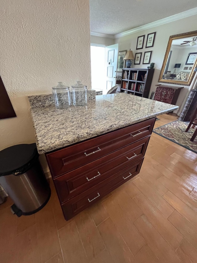 kitchen featuring reddish brown cabinets, crown molding, a textured ceiling, and wood finished floors