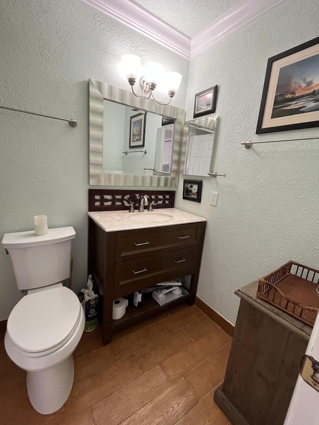 bathroom featuring a textured wall, toilet, vanity, a textured ceiling, and crown molding