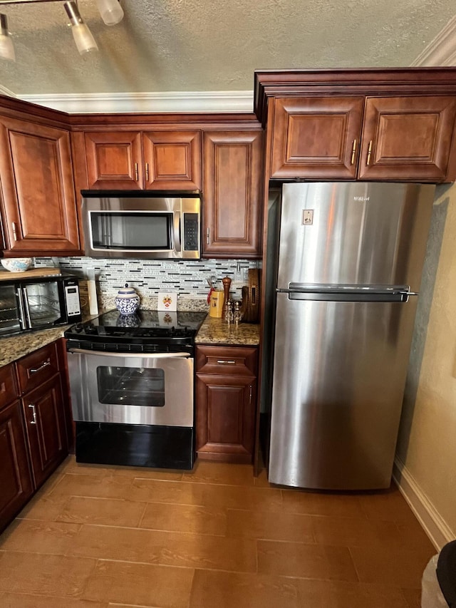 kitchen with a textured ceiling, stone countertops, stainless steel appliances, baseboards, and tasteful backsplash