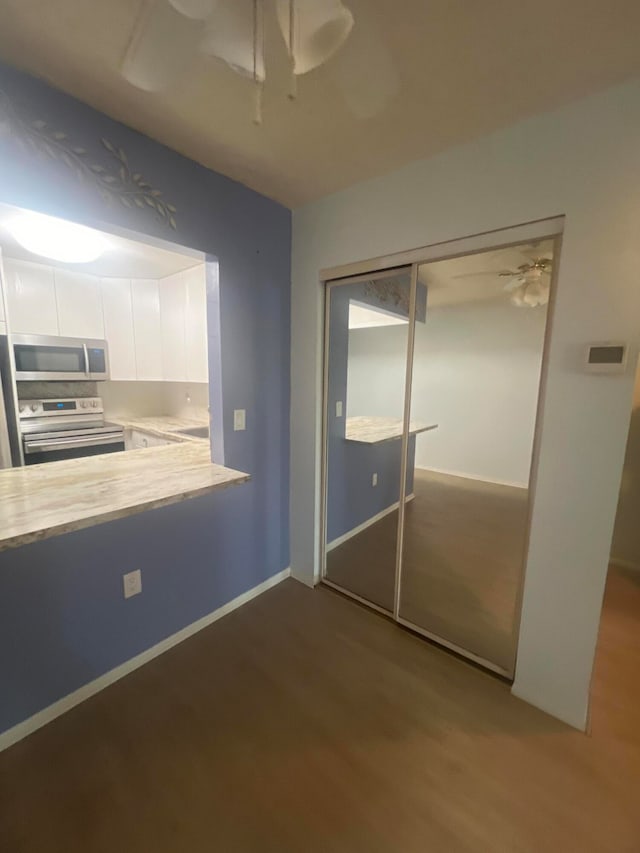 kitchen featuring stainless steel appliances, white cabinetry, hardwood / wood-style flooring, and ceiling fan