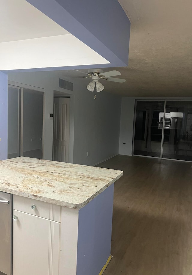 kitchen with light stone counters, dark hardwood / wood-style flooring, and ceiling fan