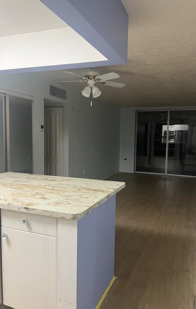 kitchen featuring ceiling fan, light stone countertops, and dark wood-type flooring