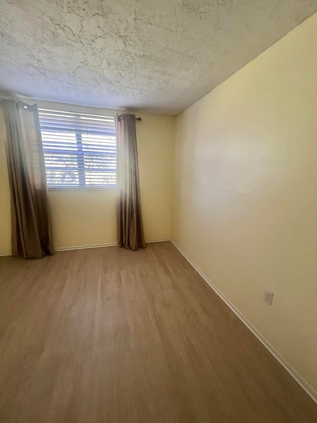 unfurnished room featuring wood-type flooring and a textured ceiling