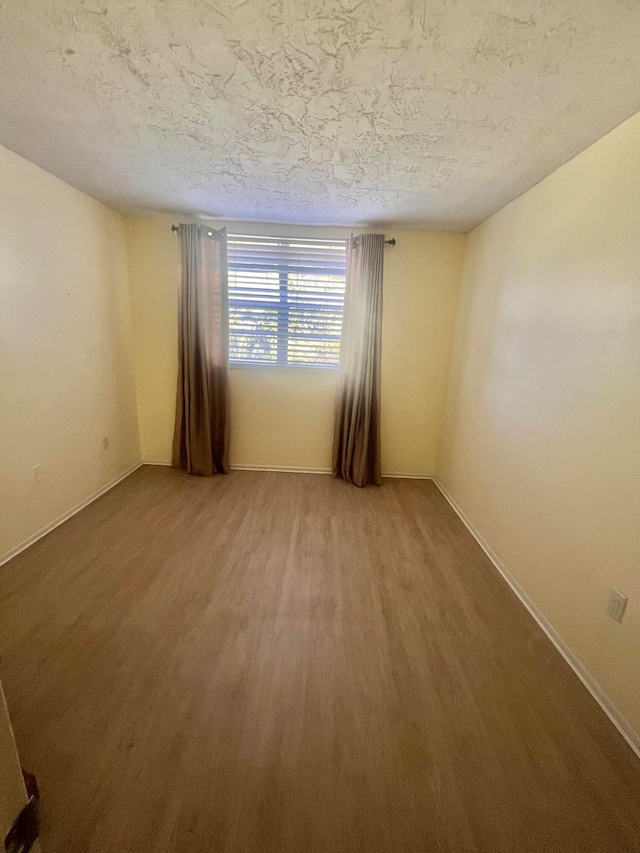 empty room with hardwood / wood-style floors and a textured ceiling