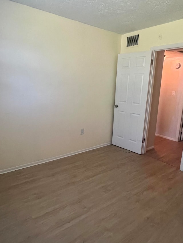 unfurnished room with wood-type flooring and a textured ceiling