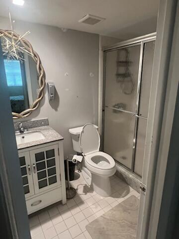 bathroom with vanity, tile patterned floors, toilet, a shower with shower door, and a chandelier