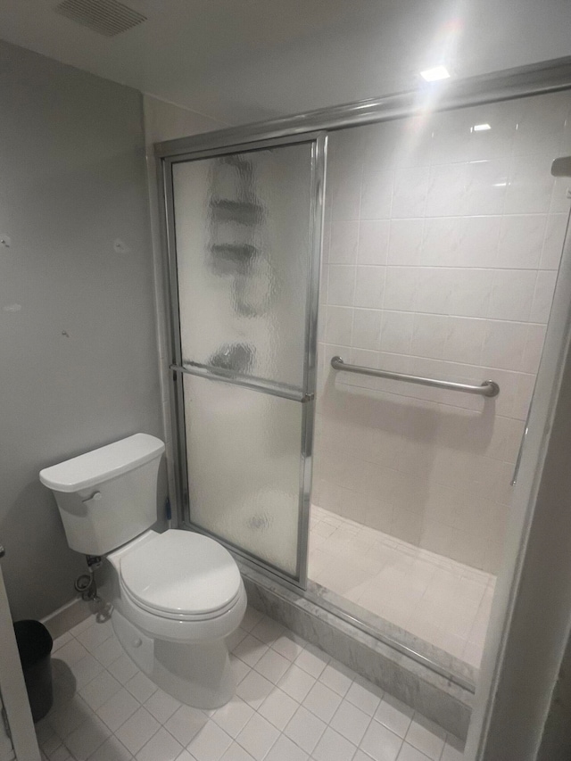 bathroom featuring tile patterned floors, a shower with door, and toilet