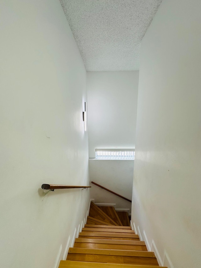 stairway featuring hardwood / wood-style floors and a textured ceiling