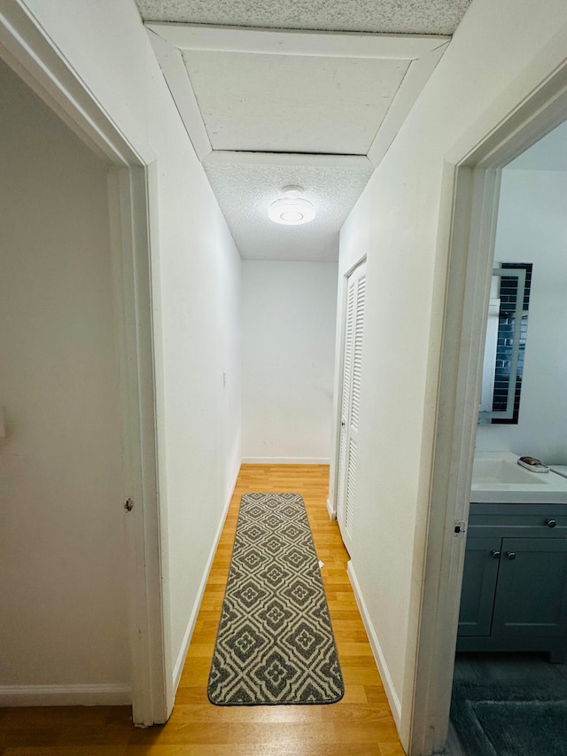 hallway with light hardwood / wood-style flooring and a textured ceiling