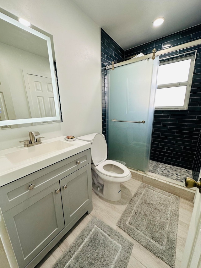 bathroom with wood-type flooring, vanity, toilet, and an enclosed shower