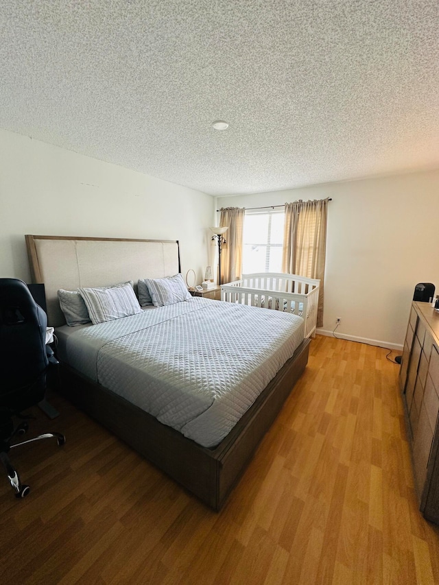 bedroom with a textured ceiling and light wood-type flooring