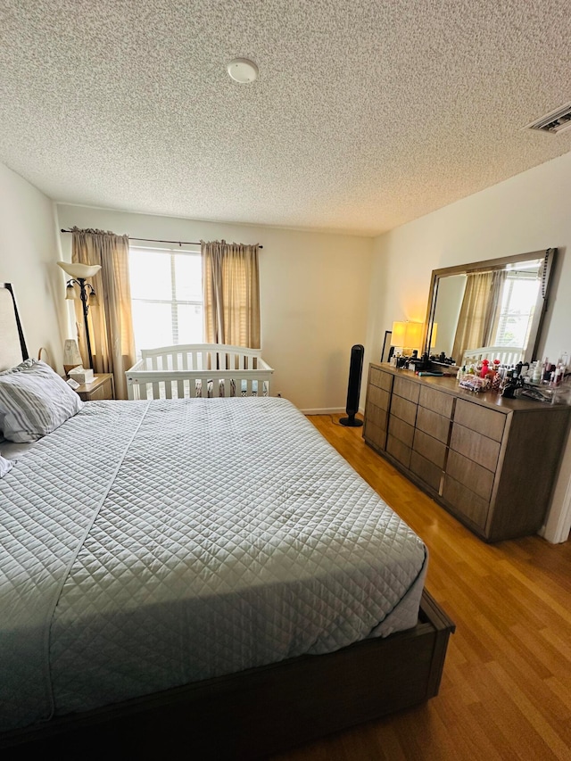 bedroom with hardwood / wood-style flooring, a textured ceiling, and multiple windows