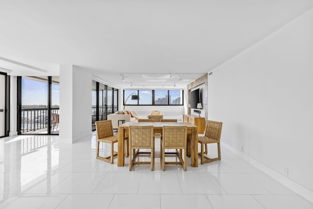 dining area featuring a wealth of natural light, a wall of windows, light tile patterned floors, and track lighting