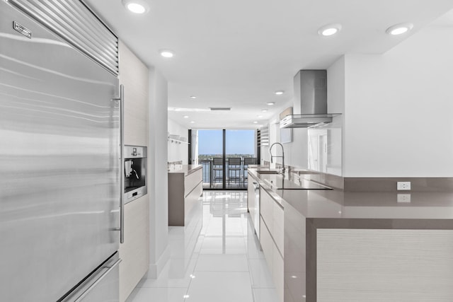 kitchen with light tile patterned flooring, floor to ceiling windows, wall chimney exhaust hood, built in refrigerator, and black electric stovetop