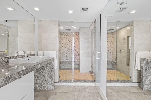 bathroom with tile walls, walk in shower, sink, and tile patterned floors