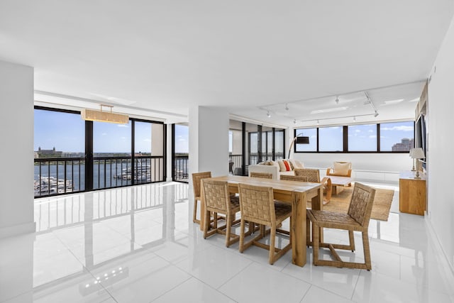 tiled dining space featuring rail lighting and a water view