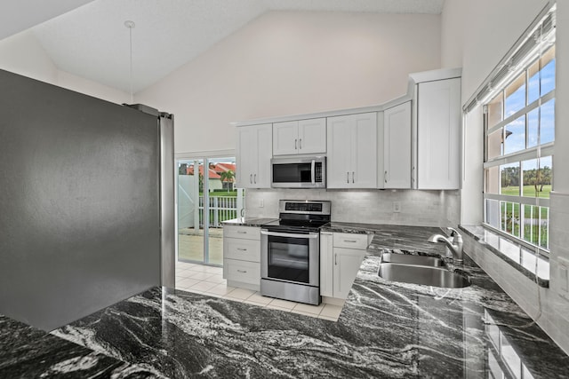 kitchen with stainless steel appliances, white cabinets, sink, high vaulted ceiling, and backsplash